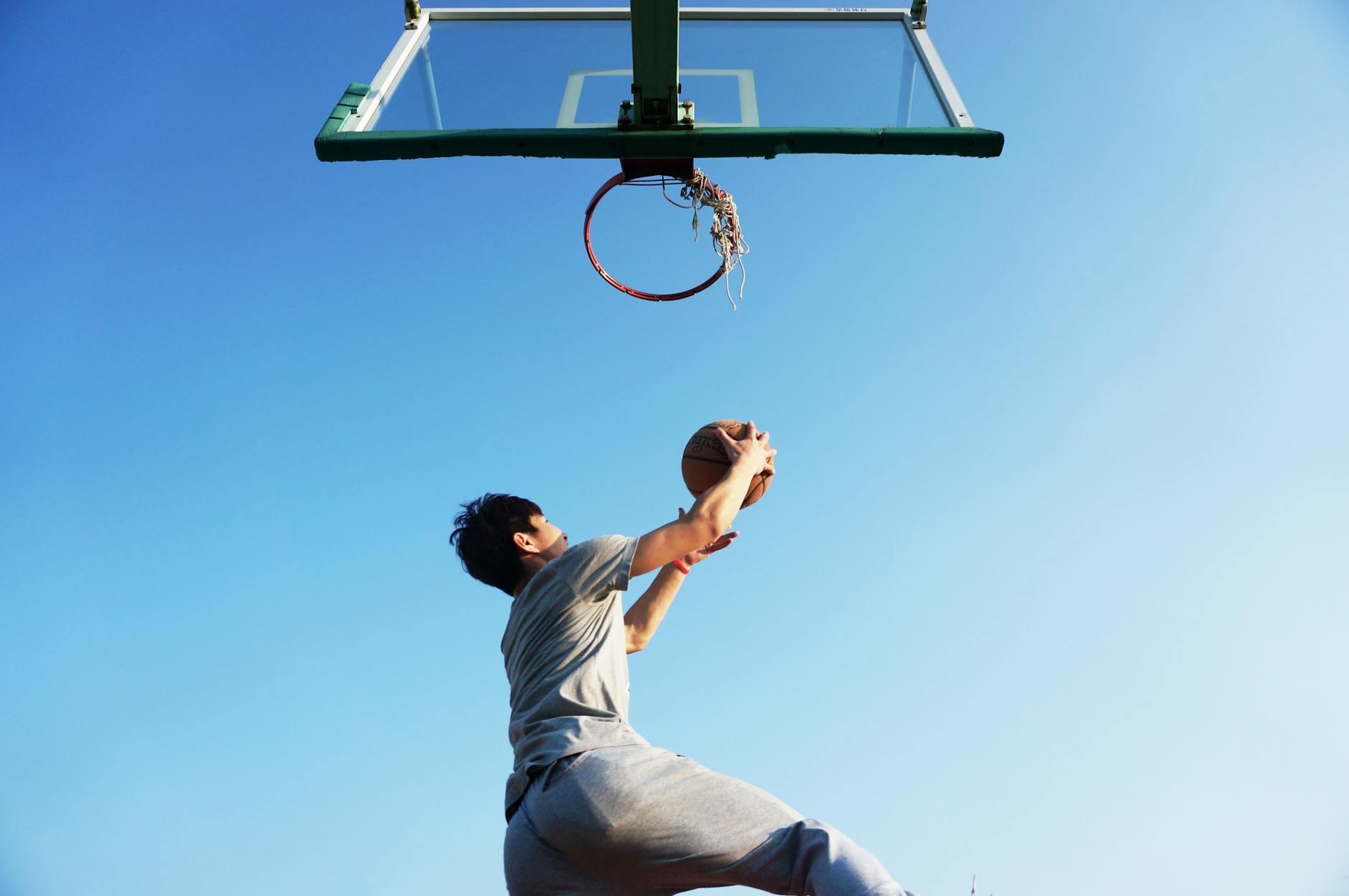 Jogador de basquete se preparando para fazer uma cesta de costas, demonstrando autoconfiança e foco durante o treino.