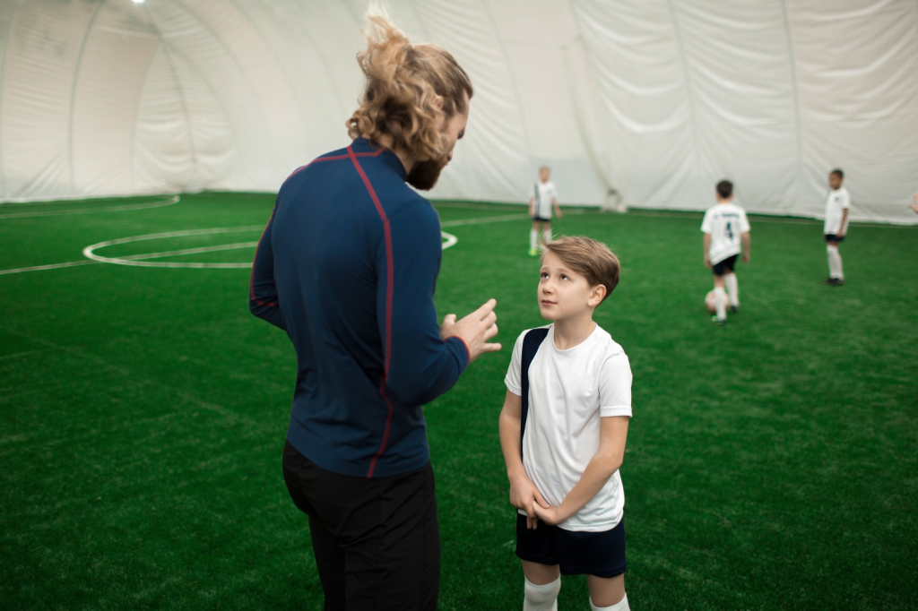 Atleta criança conversando com seu treinador sobre o seu desempenho no treino