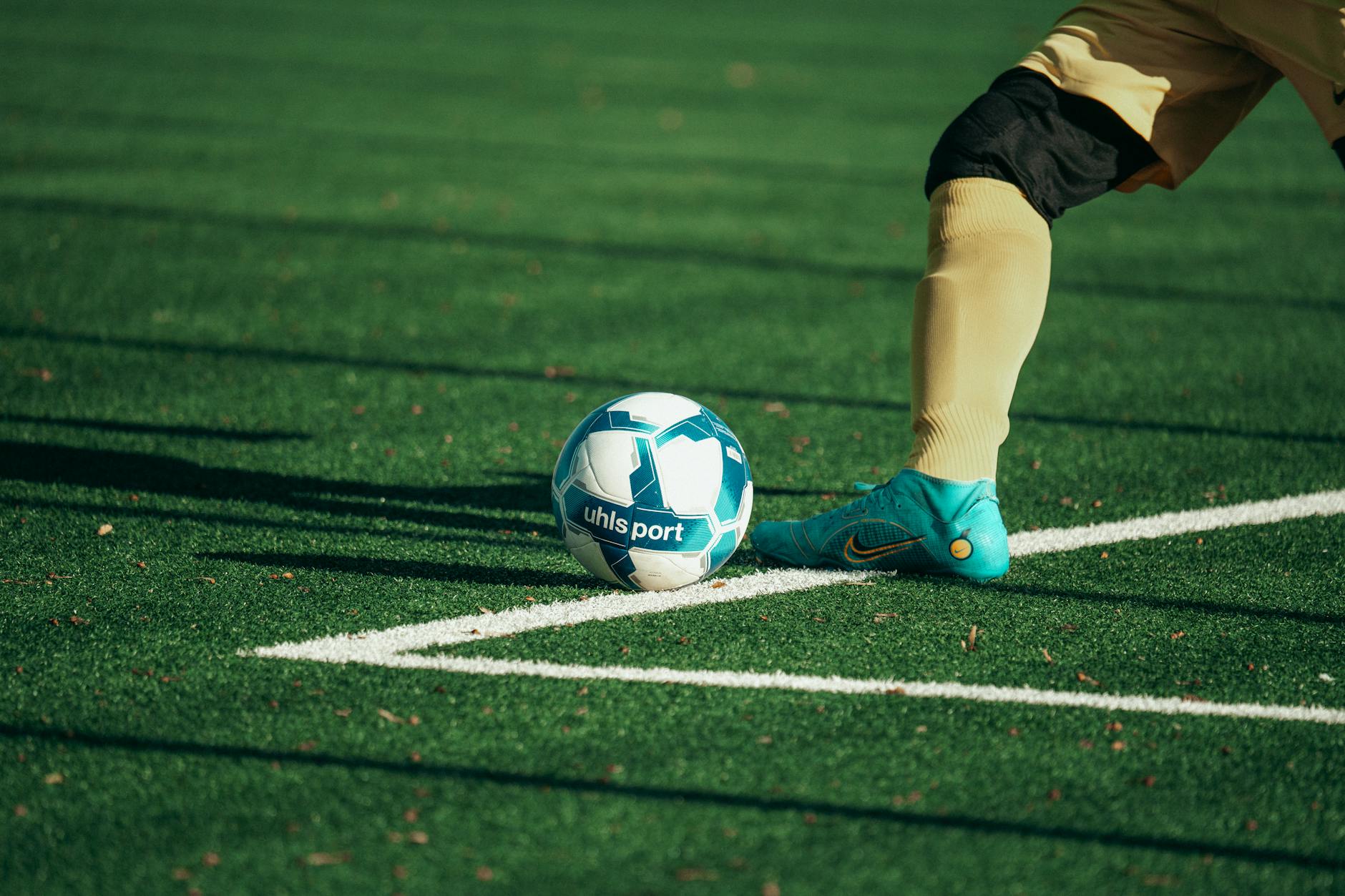 Goleiro de futebol, chutando a bola com força para reiniciar o jogo após a saída de bola em um campo de grama society.