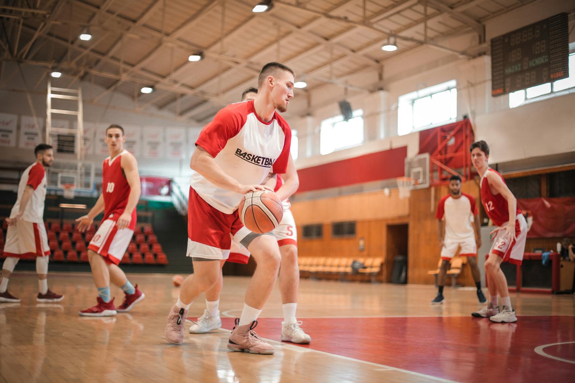 Time de basquete em treino, com um jogador segurando a bola, focado e buscando o passe, demonstrando concentração e plena autoconfiança de que fará a jogada certa.