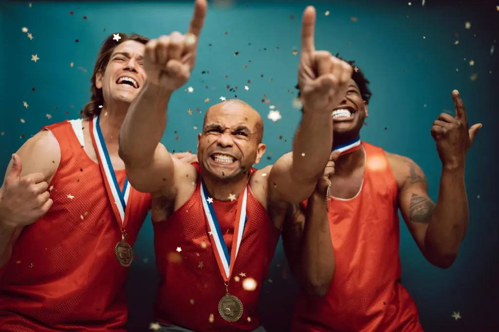 Três homens celebrando no pódio com medalhas de ouro, radiantes de felicidade e motivação pela vitória conquistada.